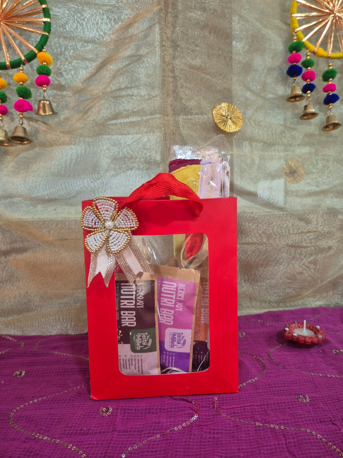 A Red Gift Bag filled with three millet nutri bars and single bhandhanwar