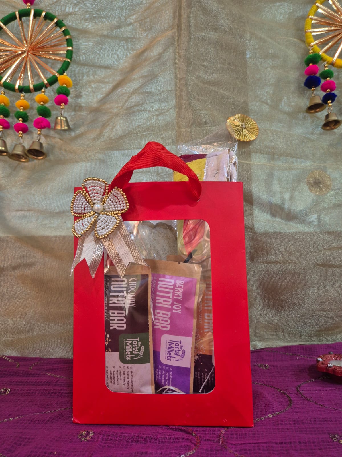 A Red Gift Bag filled with three millet nutri bars and single bhandhanwar