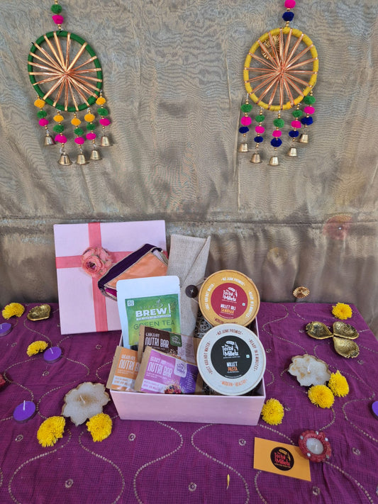 Curated gift box with coffee, tea, and pink gift packaging on purple fabric.