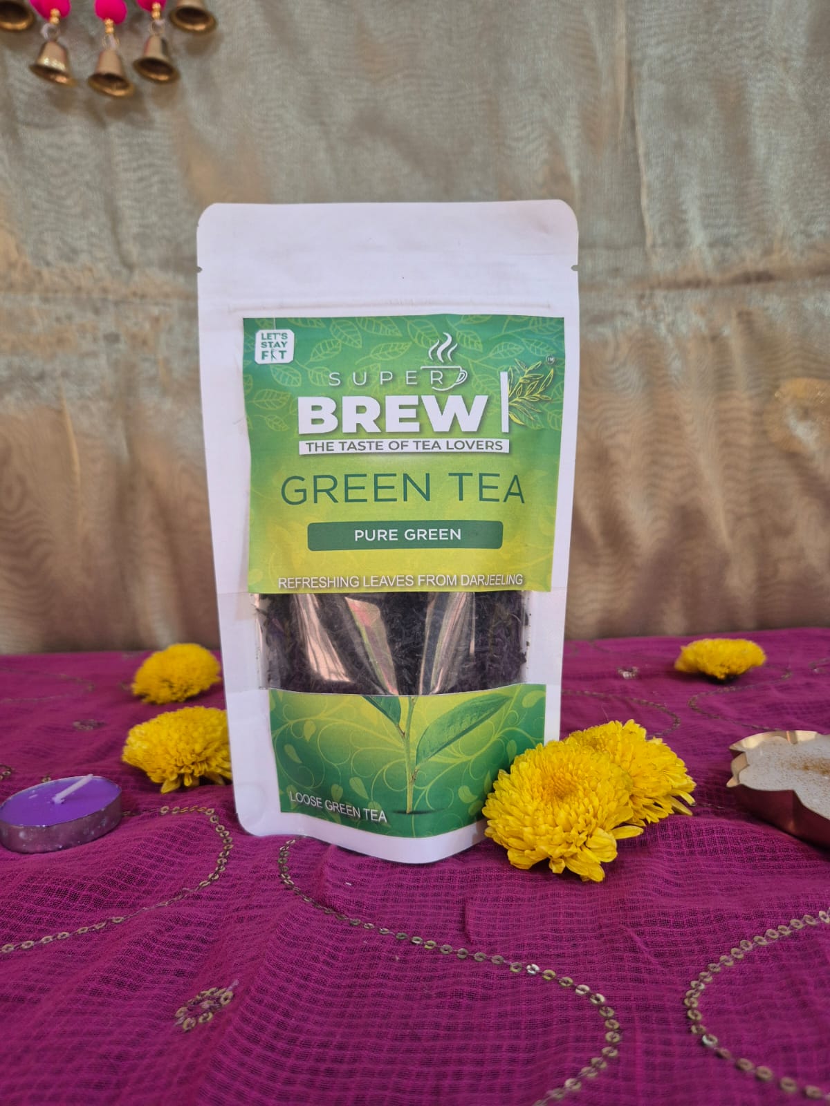 Super Brew Pure Green Tea pouch displayed on purple patterned fabric with yellow flowers.