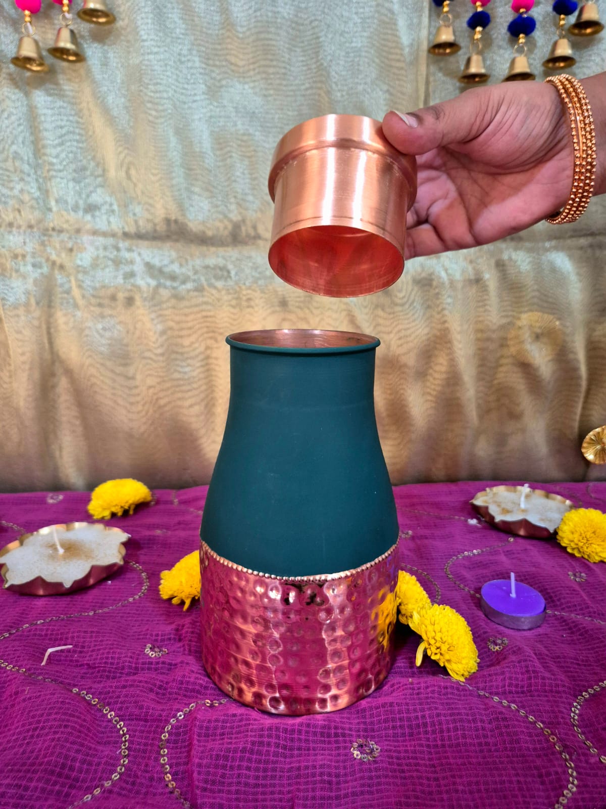 A dark teal and copper-toned metal decorative vessel Opening Lid And Pouring water in it.