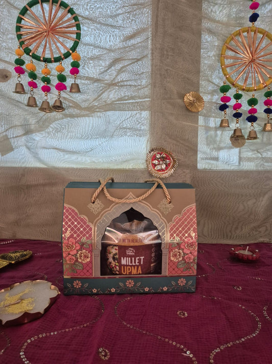 Decorative gift box with Millet Upma jar on red embroidered cloth with a traditional diya.